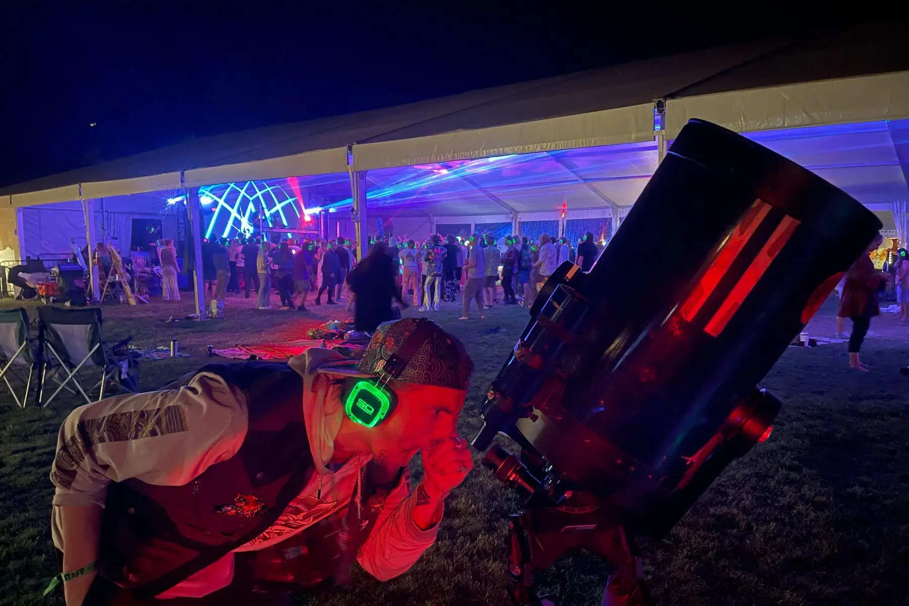 Guest looking through a large telescope at a night festival activation